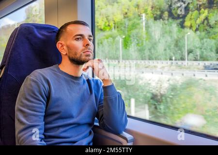 Middle aged man holds his hand to his chin and looks enjoying the views of nature and small town in the valley river Stock Photo