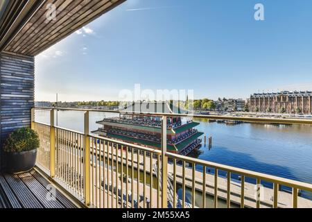 a boat going down the river on a sunny day with blue sky and white clouds in the photo is taken from a balcony Stock Photo