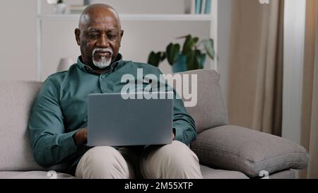 African American bald bearded businessman teacher writer entrepreneur checking data online use computer application connection wifi network at home Stock Photo