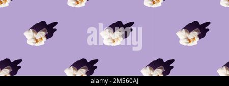 Delicious popcorn on a purple background. Seamless pattern. Banner. Culture of cinema ,domestic leisure with friends . Stock Photo
