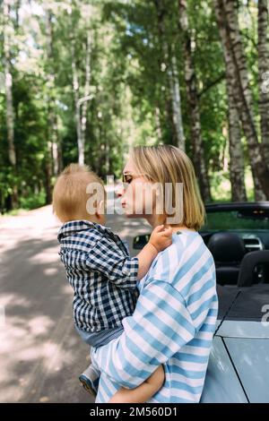 Mom and little son in a convertible car. Summer family road trip to nature Stock Photo