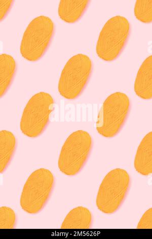 Pattern made of skein of yellow wool thread on a pink background. Creative composition. Stock Photo