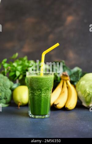 Jars of healthy green smoothie with fresh spinach on grey wooden table, closeup. Detox diet concept: green vegetables on wooden table. Stock Photo