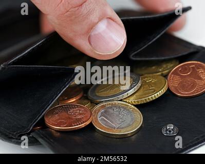 Male hand checking black leather wallet with euro coins, close-up of a open purse with loose change Stock Photo