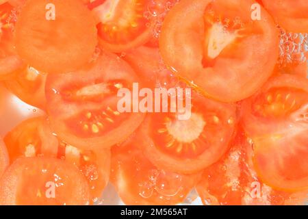 Close-up fresh slices of juicy tomato on white background. Slices of tomato in sparkling water on white background, closeup Stock Photo