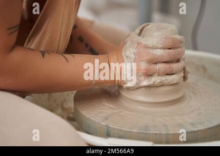 Close-up view of a woman modelling clay on potters wheel in a ceramic workshop. Craft, art and hobbies concept. Stock Photo