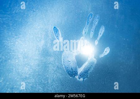 Warm hand marks on frozen glass and bright sunlight outside Stock Photo