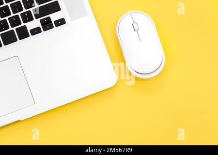 Computer mouse and laptop on a yellow background isolated, flat lay. Stock Photo