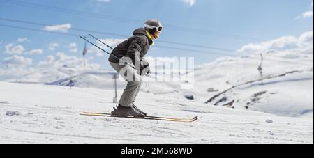 Full length profile shot of a man skiing in a ski resort Stock Photo