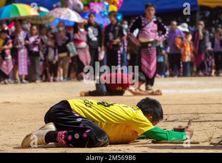 Hmong hill tribe men playing top spinning competition (traditional game of tujlub which involves spinning wooden tops hurled with string and sticks. While one top is still spinning, another person tries to hit it. If they don't hit it, they're out. If they do hit it, the winner is the one whose top continues spinning the longest.) during the Hmong New Year celebrations. In December or January, the Hmong celebrate their new year, called Noj Peb Caug (pronounced Nor Pe Chao). A larger public celebration takes place at an outdoor venue, There are many activities during this event, such as top-spi Stock Photo