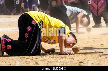 Hmong hill tribe men playing top spinning competition (traditional game of tujlub which involves spinning wooden tops hurled with string and sticks. While one top is still spinning, another person tries to hit it. If they don't hit it, they're out. If they do hit it, the winner is the one whose top continues spinning the longest.) during the Hmong New Year celebrations. In December or January, the Hmong celebrate their new year, called Noj Peb Caug (pronounced Nor Pe Chao). A larger public celebration takes place at an outdoor venue, There are many activities during this event, such as top-spi Stock Photo