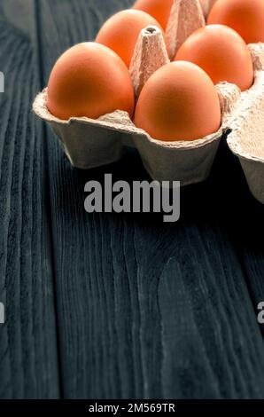 Brown chicken eggs in a cardboard tray on a black wooden table Stock Photo