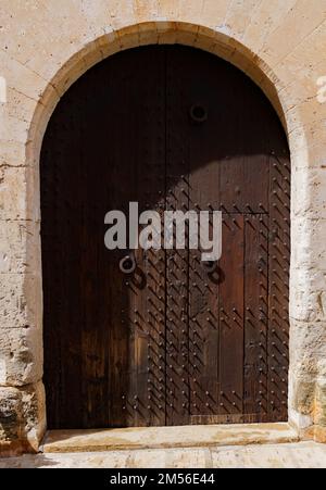 Wooden dark brown door of old stone house Stock Photo