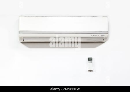White air conditioner hanging on white wall.Dirty air conditioner. Stock Photo