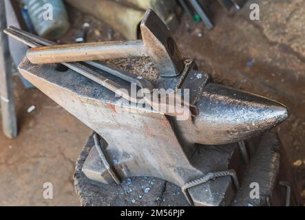 hammer and tongs lie on an anvil in a workshop Stock Photo
