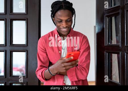 Cheerful inspired African American man smiling using smartphone for chatting with girlfriend Stock Photo