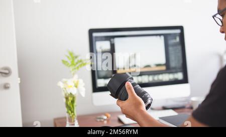 A young photographer looking at target in his hand while working on computer Stock Photo