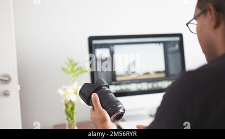 A young photographer looking at target in his hand while working on computer Stock Photo