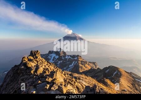 Erupting Popocatepetl volcano above the mist in Mexico from Iztaccihuatl Stock Photo