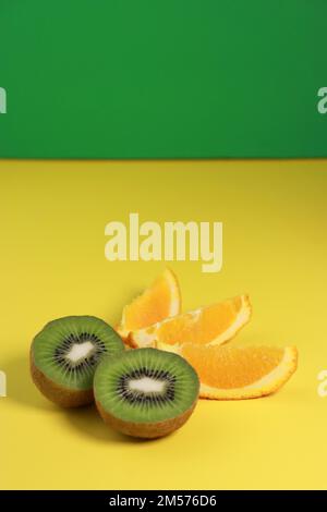 close up of kiwi fruit and orange slices on yellow background  Stock Photo