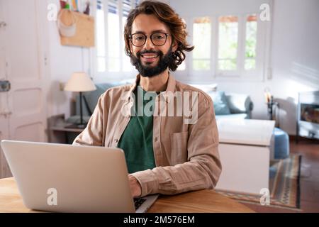 Cheerful young programmer looking at camera while working at his home Stock Photo