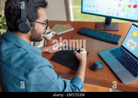 Male designer works in home office drawing on graphic tablet. Freelancer working on project Stock Photo