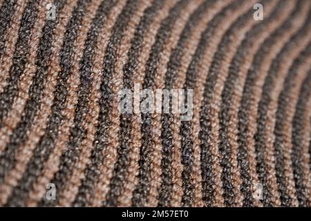 Dark relief carpet texture with asymmetric rows for unusual background. Close up view of strip pattern of synthetic tight wavy rows. Concept of textures and background. Stock Photo