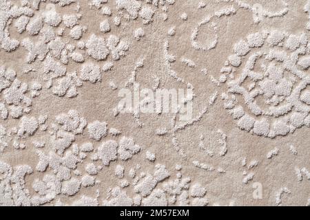 Fragment of decorative velours carpet fabric pattern, background photo texture. Close up of geometric beige and white short pile carpet ornament, upholstery fabric. Backgrounds and textures concept. Stock Photo