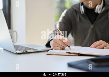 cropped and close-up image, Smart young Asian male college student doing his school homework, taking notes on school book. Stock Photo