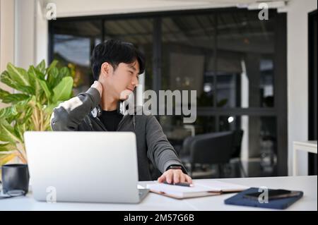 Happy young Asian male office worker or college student relaxing after finish work at his desk. Stock Photo
