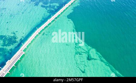 A drone view of the Busselton Jetty in the clear turquoise ocean water on a sunny day in Busselton, Australia Stock Photo