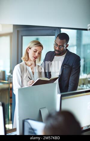 This is what your day is looking like so far. two colleagues using a notebook together at work. Stock Photo