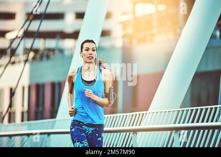The sun never sets on your dedication. a young woman out in the city for her morning run. Stock Photo