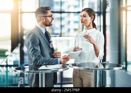 It takes two to do the business tango. two colleagues using a digital tablet together in a modern office. Stock Photo