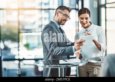 Getting even more done with modern tech. two colleagues using a digital tablet together in a modern office. Stock Photo