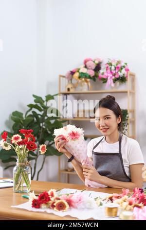 Flower shop concept, Female florist smile and holds colorful flower bouquet with paper and ribbon. Stock Photo
