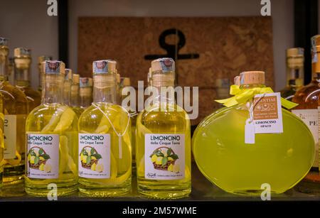 Manarola, Italy - June 1, 2022: Bottles of traditional Cinque Terre limoncino, lemon liqueur for sale on display, local old town gift shop Stock Photo