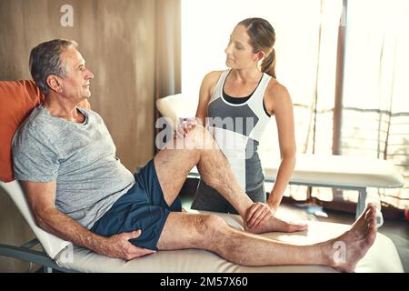 Helping him to become more mobile. a senior man being treated by a physiotherapist. Stock Photo