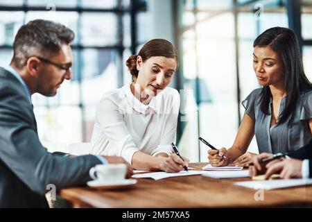 Three times the brainpower on this project. a group of colleagues having a meeting in a modern office. Stock Photo