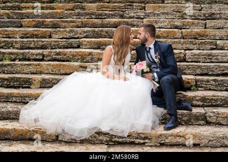 Newly married couple kissing and looking at each other on some stone stairs Stock Photo