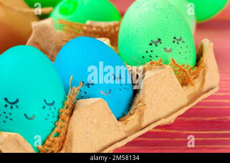 Blue and green colored Easter eggs with drawn funny faces Stock Photo