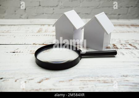 Model House and magnifying glass on wooden background Stock Photo