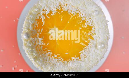 Cake with orange and coconut shavings spun on a pink background. Stock Photo