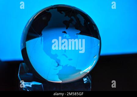 A person holding a world globus, sphere against a blue light Stock Photo
