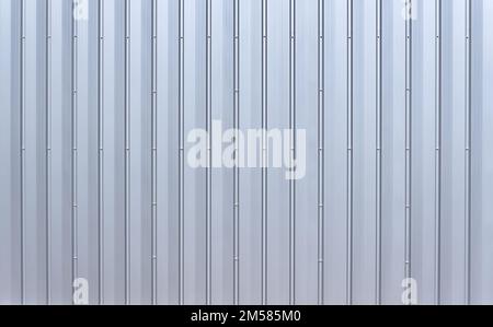 Silver colored aluminum wall paneling with vertical grooves and hex bolts Stock Photo