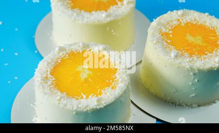 Small cakes with orange and coconut on a blue background. Stock Photo