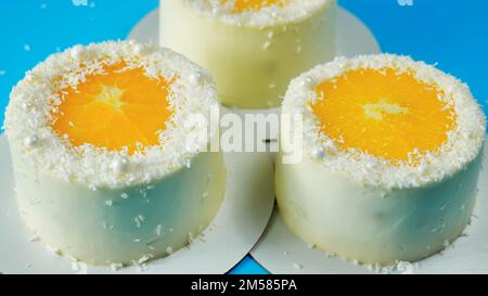 Small cakes with orange and coconut on a blue background. Stock Photo