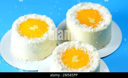 Small cakes with orange and coconut on a blue background. Stock Photo