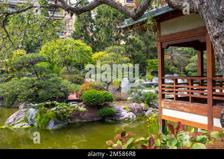 Monaco - May 3, 2022: A wood pavilion is overlooking a pond of the Japanese garden of Monaco. Taken on a sunny spring day. Stock Photo