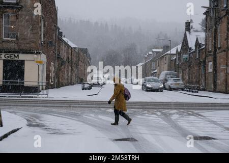 Callander, Scotland, UK. 27th December 2022. Heavy snow falling causing tricky conditions in Callander High Street for motorists and pedestrians. Credit: Craig Brown/Alamy Live News Stock Photo